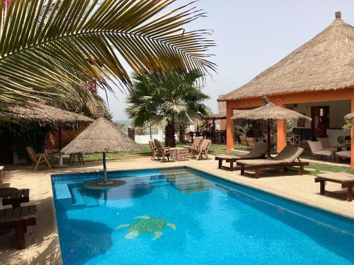 uma piscina com cadeiras e guarda-sóis ao lado de um resort em Terra Lodge Sénégal em Mbour
