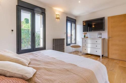 - une chambre avec un grand lit, une télévision et des fenêtres dans l'établissement JO 2024 - Maison d'architecte avec jardin, à Villeneuve-la-Garenne