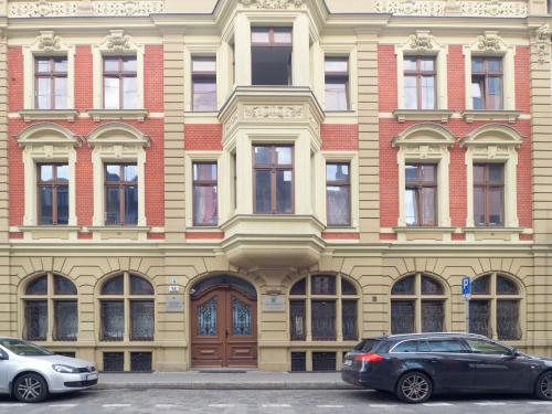 two cars parked in front of a large building at Best Apartments Św. Antoniego in Wrocław