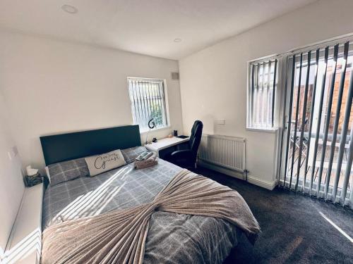 a bedroom with a bed and a desk and windows at Charming 2-Bed Apartment in Birmingham in Birmingham