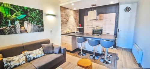a living room with a couch and a kitchen at Votre résidence de vacances avec piscine, tennis, à 2 minutes de la mer in Vallauris