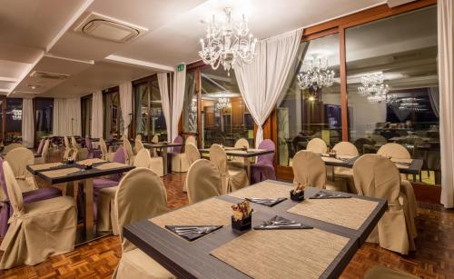 a dining room with tables and chairs and chandeliers at Grande Albergo Roma in Piacenza