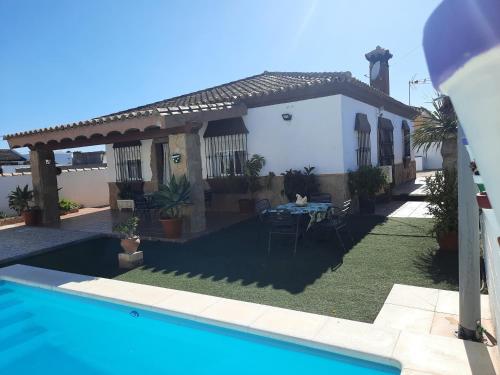 una villa con piscina frente a una casa en Casa LA PEPA, en Chiclana de la Frontera