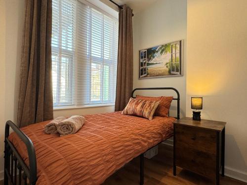 a bedroom with a bed with an orange bedspread and a window at Spanish City View 3 Stunning sea front apartment Free onsite parking in Whitley Bay