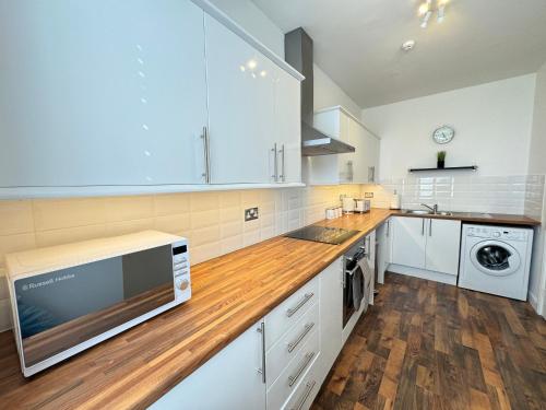 ウィットリー・ベイにあるSpanish City View 3 Stunning sea front apartment Free onsite parkingの白いキャビネットと木製のカウンタートップを備えたキッチン