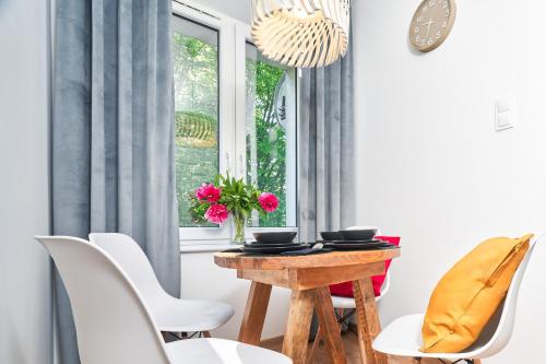 Un comedor con una mesa de madera y sillas blancas. en Apartament Emilii Plater 5, en Olsztyn
