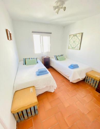 two beds in a room with white walls at Tarifa Townhouse in Tarifa