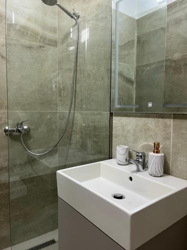a bathroom with a white sink and a shower at Lotus Apartments in Vlorë
