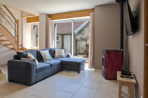 a living room with a blue couch and a tv at Le gîte du centre, parking avec recharge pour véhicule électrique in Avrecourt