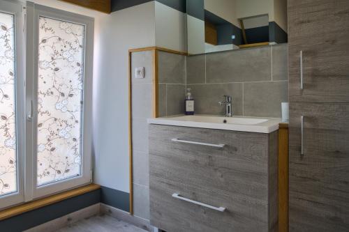 a bathroom with a sink and a window at Le gîte du centre, parking avec recharge pour véhicule électrique in Avrecourt