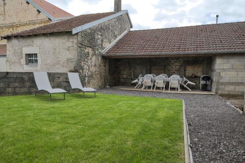 a yard with chairs and tables and a building at Le gîte du centre, parking avec recharge pour véhicule électrique in Avrecourt