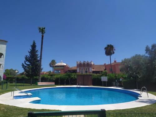 una gran piscina en un patio con palmeras en Coqueto apartamento en CalaHonda en Mijas Costa