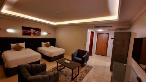 une chambre d'hôtel avec deux lits et une chaise dans l'établissement Grand Plaza Sheikh Zayed, à Kafr Abū ʼumaydah