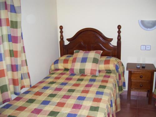 a bed with a colorful quilt and a wooden headboard at Casa Concha in Almadén de la Plata