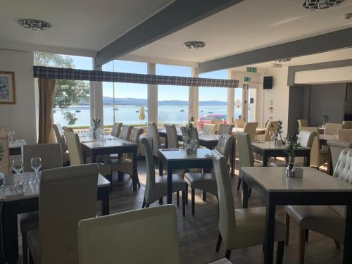 ArdrishaigにあるThe Grey Gull Hotelの水辺の景色を望むテーブルと椅子付きのレストラン