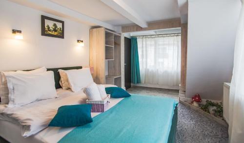 1 dormitorio con 1 cama grande con almohadas azules y blancas en Anelisse Inn, en Moieciu de Sus