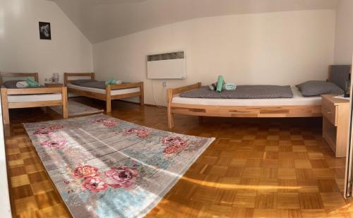 a room with two beds and a rug on the floor at Sobe Lara in Gradačac