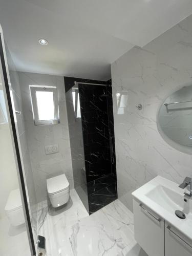 a white bathroom with a toilet and a sink at Residence LEORA in Ulcinj
