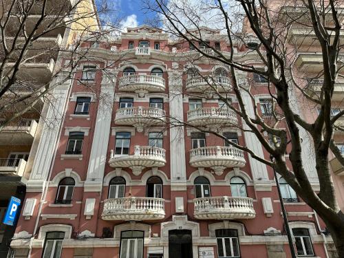 a tall red building with white balconies on it at Laniakea Suites in Lisbon