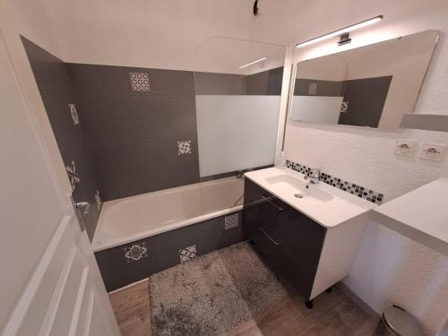 une salle de bain avec un lavabo, une baignoire et un miroir dans l'établissement appartement T2 coin montagne, à Vars