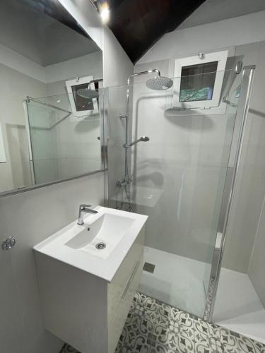 baño blanco con ducha y lavamanos en La casita de Mazo en Mazo