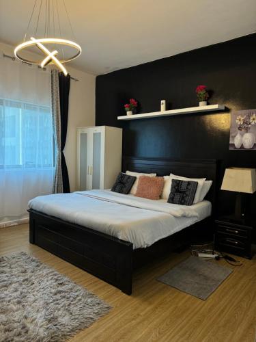 a bedroom with a large bed with a black headboard at DALA MASTER Bedroom En-suite in Sharjah