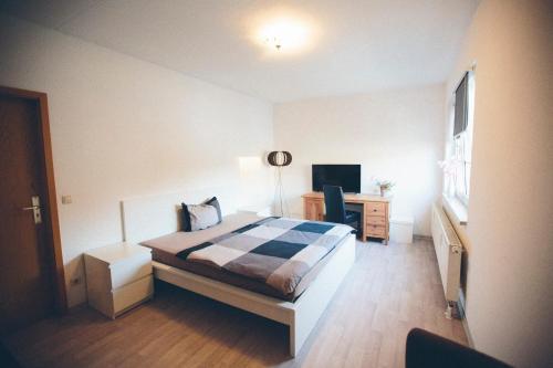 a bedroom with a bed and a desk and a television at Große & voll ausgestattete Apartments, Studios, Doppelzimmer, Workspace, Parkplatz, Netflix, Prime & schnelles Wifi in ruhiger Lage mit Garten in Rudolstadt