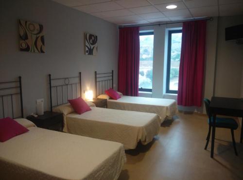 Una habitación de hotel con tres camas y una ventana. en Hostal la Molina, en Álora