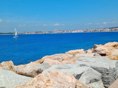 a sailboat on the water with rocks in the foreground at Quedar-se a l'Alguer in Alghero