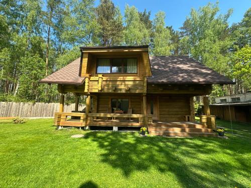 Cabaña de madera con porche en un patio en Guest house Saulainie krasti en Saulkrasti