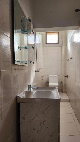 a white bathroom with a sink and a window at Diadia Apartment 1 in Dakar