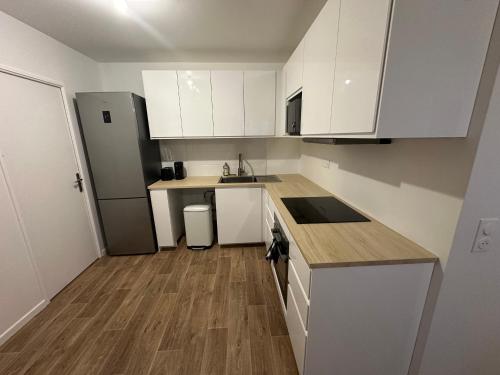 une cuisine avec des armoires blanches et un plancher en bois dans l'établissement Nid confortable près de Paris, à Bagneux
