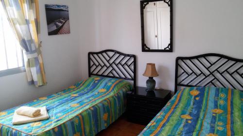 1 dormitorio con 2 camas individuales y espejo en Villa Azul, en Callao Salvaje