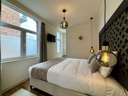 a bedroom with a bed and two windows at Maison du Roi in Liège