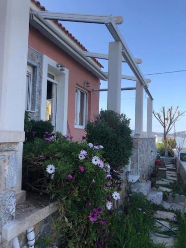 a house with a bunch of flowers in front of it at Modern house by the sea in Apidias Lakos