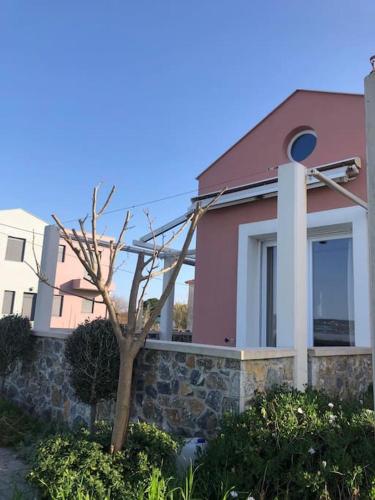 a pink house with a tree in front of it at Modern house by the sea in Apidias Lakos