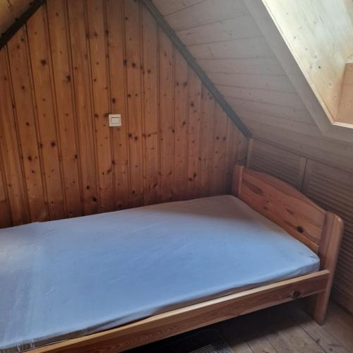 a bed in a room with a wooden wall at Apartment da Luiz Salvatore in Wurmlingen