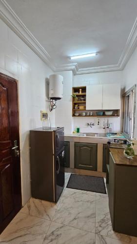 a large kitchen with a refrigerator and a sink at Résidences C-Irène Angré in Abidjan