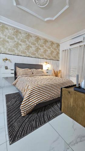 a bedroom with a large bed with a striped comforter at Résidences C-Irène Angré in Abidjan