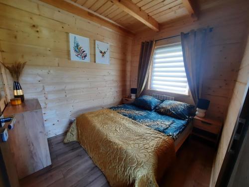 a bedroom with a bed in a log cabin at Domek przy lesie na Roztoczu in AdamÃ³w