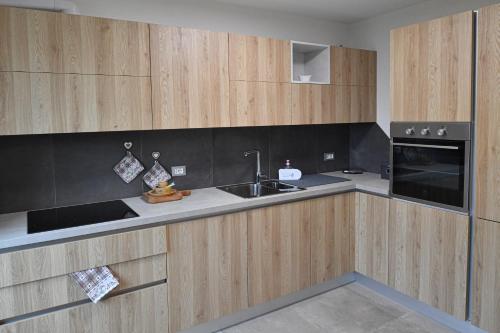 - une cuisine avec des placards en bois et un évier dans l'établissement Appartamento Bucaneve, à Pieve Tesino