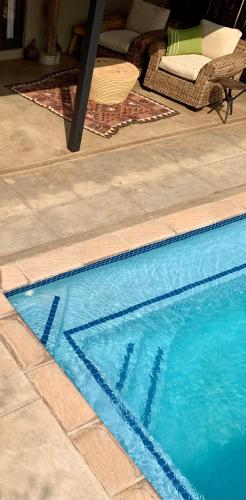 a blue swimming pool with a table next to it at Rooibos Luxury Bush Cottage in Hoedspruit