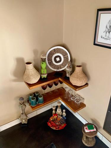 a room with a shelf with vases and a fan at Rooibos Luxury Bush Cottage in Hoedspruit