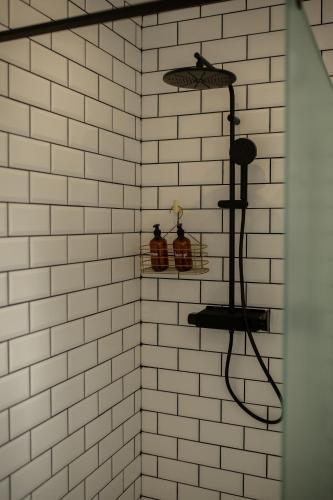 une douche carrelée blanche avec deux étagères au mur dans l'établissement La halte ducale #1, à Charleville-Mézières