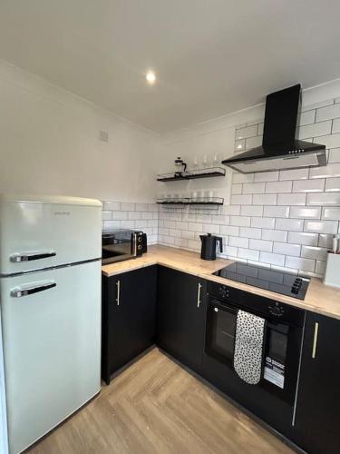 a kitchen with a white refrigerator and black cabinets at Brand new City centre apartment with parking in Cardiff