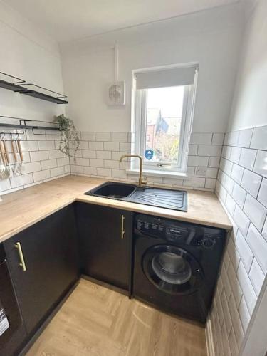 a kitchen with a sink and a washing machine at Brand new City centre apartment with parking in Cardiff