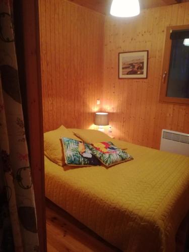 a small bedroom with a bed with yellow sheets at CHALET 9 "Pensée" in Garin