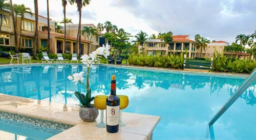 a bottle of wine sitting next to a swimming pool at Villa De Palma -Oceanfront community w generator in Sabana