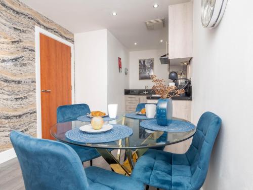 a dining room with a glass table and blue chairs at Central Birmingham Apartment with Balcony & Netflix in Birmingham