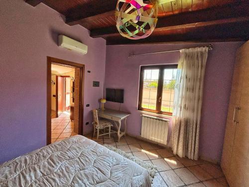 um quarto com paredes roxas, uma cama e uma secretária em La casetta holiday em Fiumicino